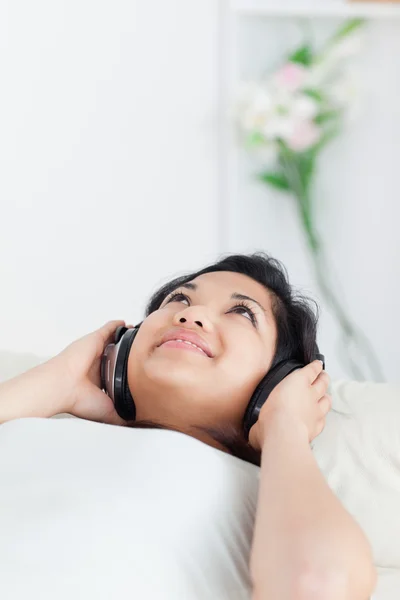 Mujer acostada en un sofá con auriculares — Foto de Stock