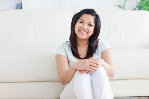 Vrouw glimlacht als ze zit op de vloer in een woonkamer — Stockfoto