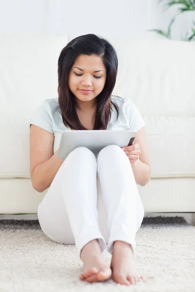 Femme assise sur le sol tout en jouant avec une tablette tactile — Photo