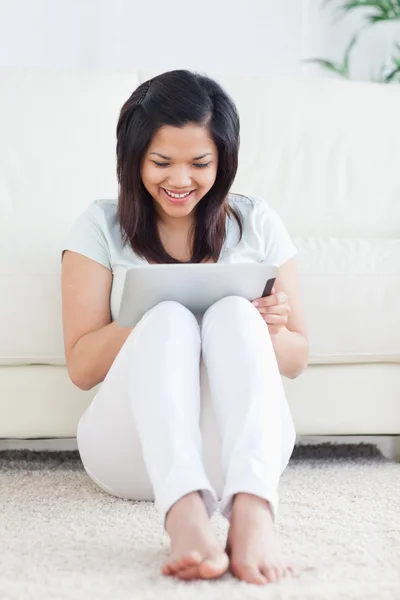 Lachende vrouw zittend op de vloer tijdens het spelen met een tactiele — Stockfoto