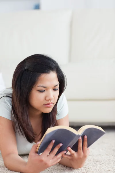 Mujer tendida en el suelo mientras lee un libro — Foto de Stock