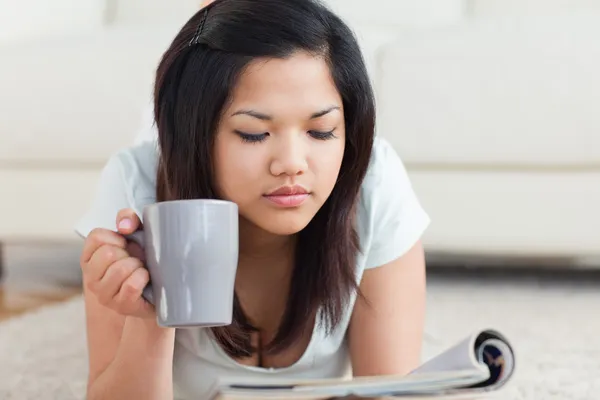 Woman holding a mug while reading a magazine — Stock Photo, Image