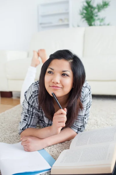 Denken vrouw liggend op de vloer met een boek en een notebook — Stockfoto