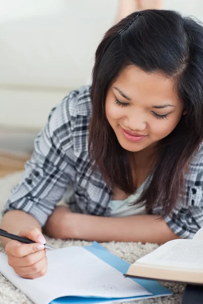 Mujer tendida en el suelo mirando un cuaderno — Foto de Stock