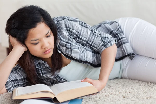 Femme lisant un livre alors qu'elle s'allonge sur le sol — Photo