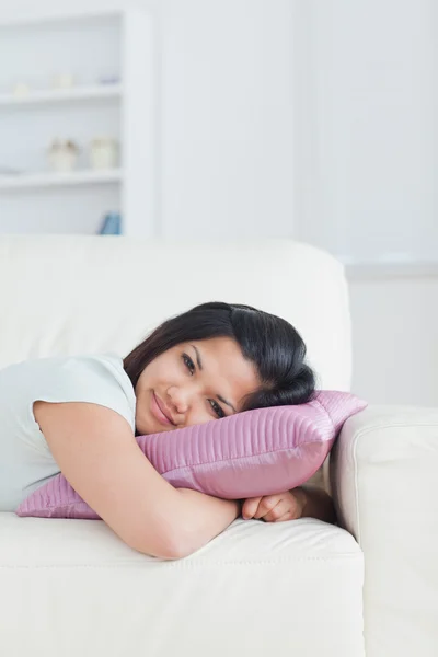Mulher relaxando em um sofá com a cabeça em um travesseiro — Fotografia de Stock