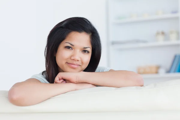 Lachende vrouw overschrijding van haar armen op een witte sofa — Stockfoto