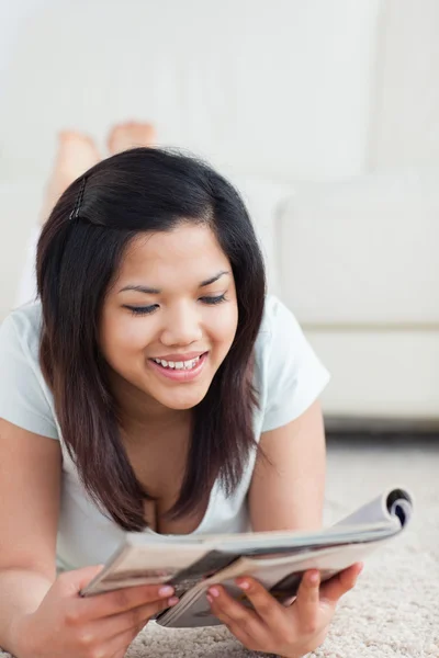 La donna sorride mentre legge una rivista Immagine Stock