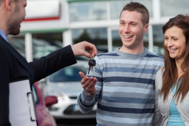 Couple receiving car keys by a dealer clipart