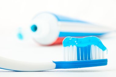 Toothbrush with blue toothpaste next to a tube of toothpaste clipart