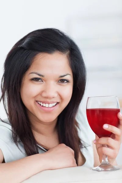 Close-up de uma mulher sorridente segurando um copo de vinho tinto — Fotografia de Stock