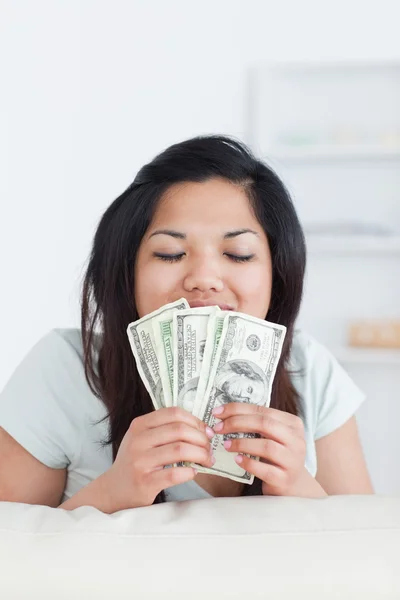 Frau schließt die Augen, als sie ein paar Dollarscheine in der Hand hält — Stockfoto