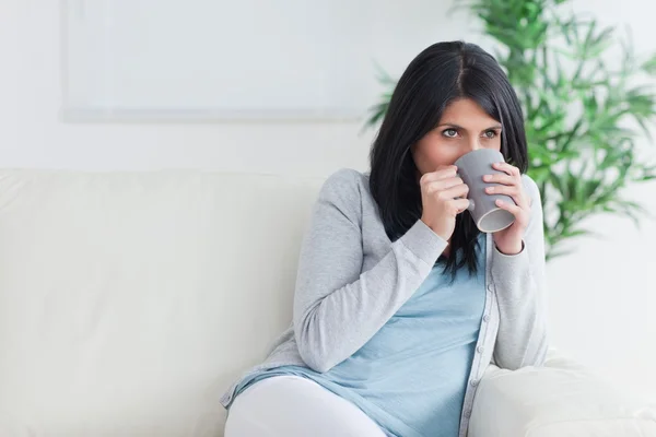 Kvinna dricka ur en mugg och hålla med två händer — Stockfoto