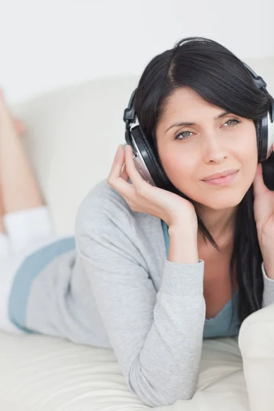 Woman wearing headphones and laying on a couch — Stock Photo, Image