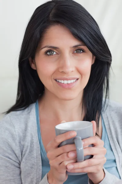 Close-up de uma mulher sorrindo enquanto segurava uma caneca — Fotografia de Stock