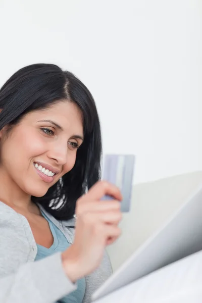 Mujer mirando una tableta táctil mientras sostiene una tarjeta — Foto de Stock