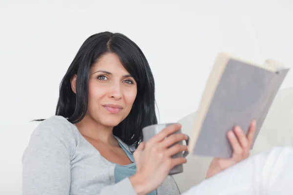 Mujer sosteniendo una taza gris y un libro — Foto de Stock