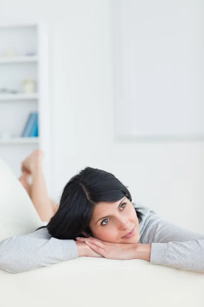 Kvinna på en soffa med huvudet vilande på hennes armar — Stockfoto