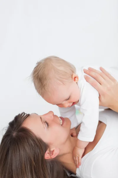 Χαμογελώντας μελαχρινή γυναίκα που παίζει με το μωρό — Φωτογραφία Αρχείου