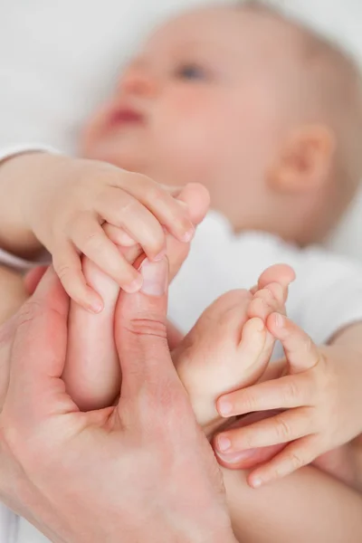 Händerna röra fötterna av en baby — Stockfoto