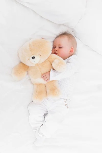 Baby sleeping while holding a teddy bear — Stock Photo, Image