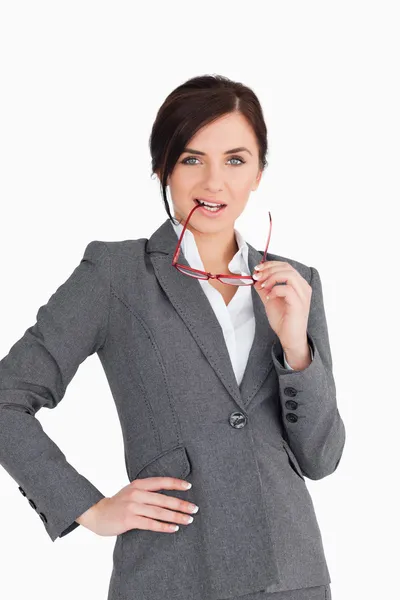 Verleidelijke zakenvrouw haar bril aanbrengend haar mond — Stockfoto