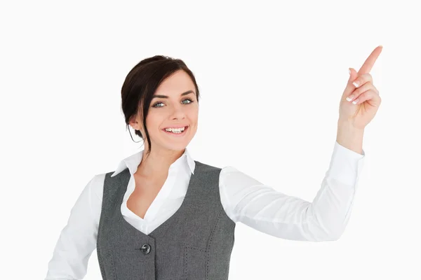 Smiling well-dressed brunette pointing up — Stock Photo, Image