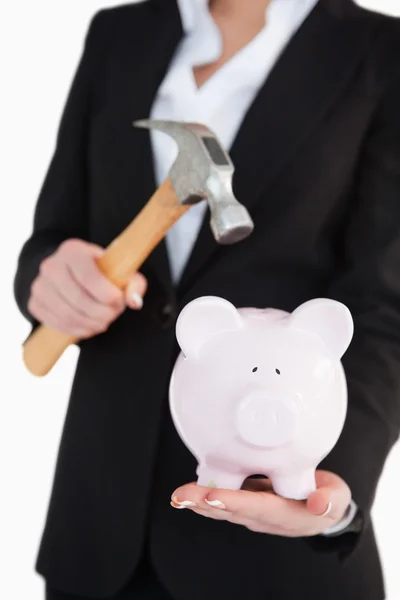 Zakenvrouw holding een piggy-bank en een hamer — Stockfoto