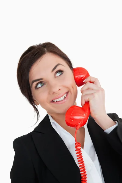 Happy woman in suit using a red dial telephone while looking up — Stock Photo, Image