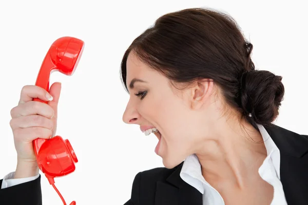 Mulher de terno gritando contra um telefone mostrador vermelho — Fotografia de Stock