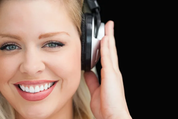 Sorrindo mulher loira ouvindo música através de fones de ouvido — Fotografia de Stock