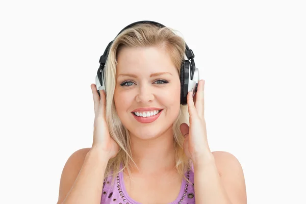 Mujer rubia sonriente poniendo sus manos en sus auriculares — Foto de Stock