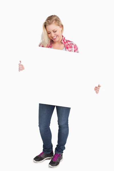 Femme blonde souriante regardant une pancarte — Photo