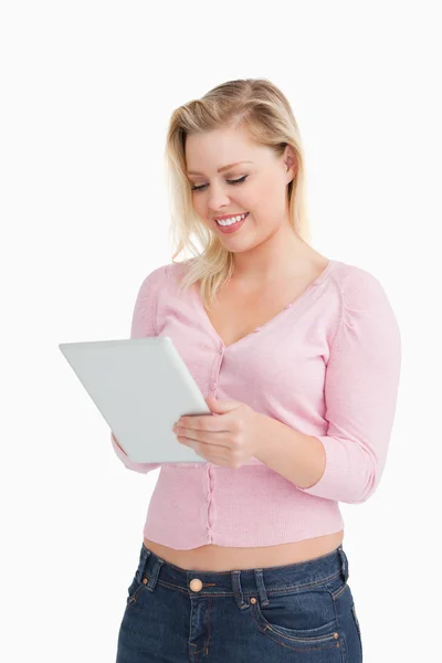 Femme blonde souriante debout tout en touchant sa tablette pc — Photo