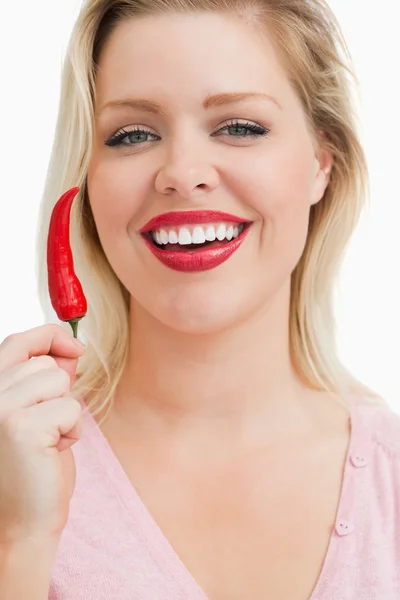 Fröhliche blonde Frau zeigt ein Chili — Stockfoto