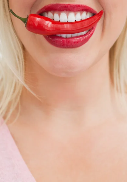 Mulher loira feliz colocando um chili entre os dentes — Fotografia de Stock