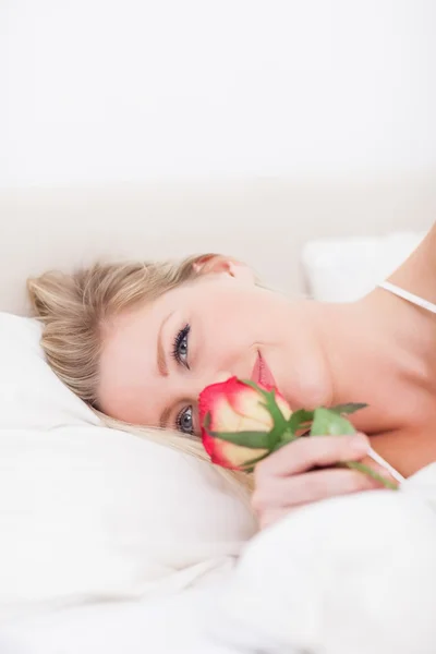Femme aux yeux bleus sentant une rose — Photo