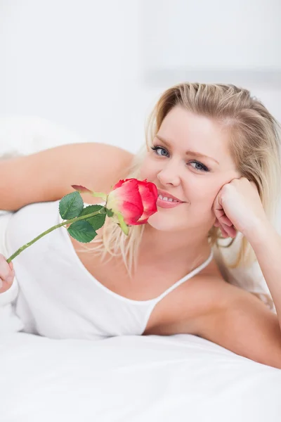 年轻女子嗅到一朵粉红色的玫瑰 — 图库照片