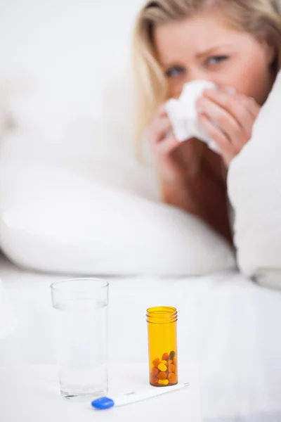 Medicines with a blonde woman sneezing — Stock Photo, Image