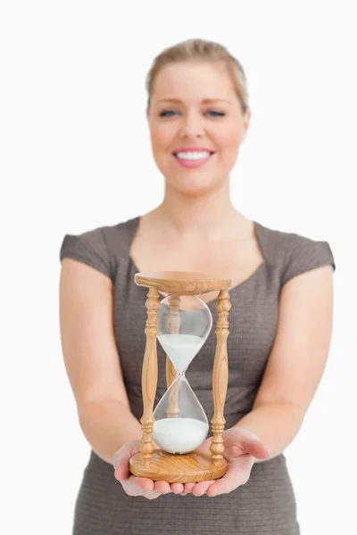 Mujer sonriendo mostrando un reloj de arena — Foto de Stock