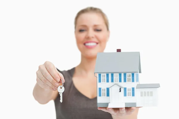 Mujer borrosa mostrando una casa modelo y una llave —  Fotos de Stock