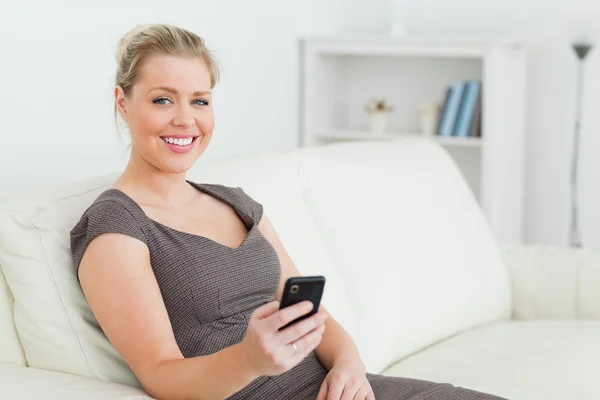 Frau lächelt, während sie ihr Handy benutzt — Stockfoto