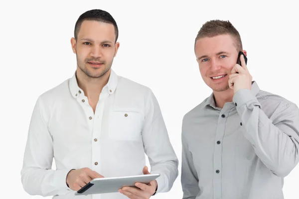 Två leende män med en telefon, en tablett dator — Stockfoto