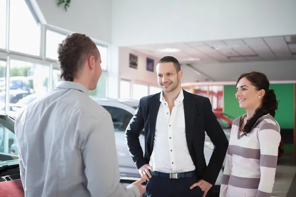 Autohandelaar chatten met een paar — Stockfoto