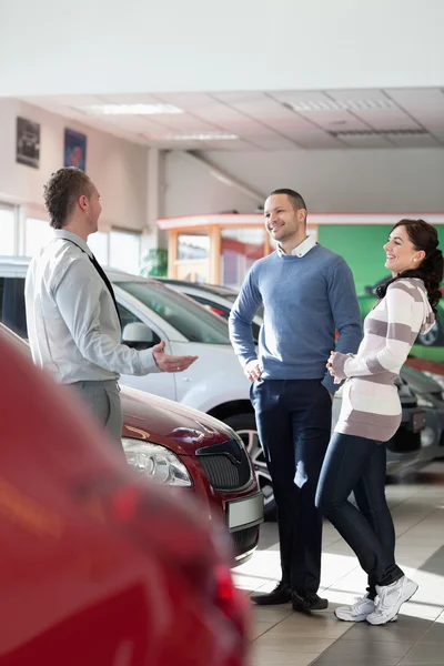 Sorrindo casal conversando com um concessionário de carros — Fotografia de Stock