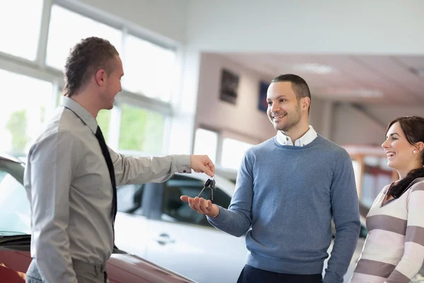 Säljare ger bilnycklarna till ett par — Stockfoto