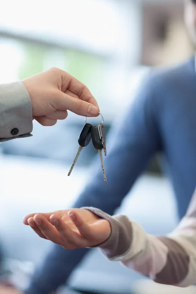 Verkoper houdt sleutels over de hand van een klant — Stockfoto