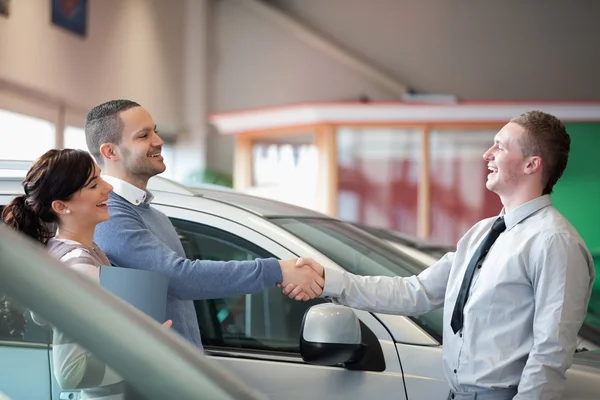 Salesman smiling while shaking the hand of a customer — Stock Photo, Image