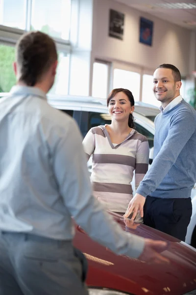 Couple smiling and chatting with a salesman — Stock Photo, Image