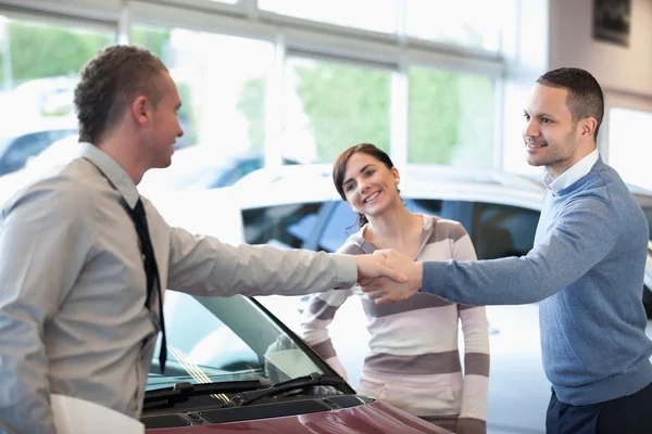 Carro negociante apertando a mão com um homem sorridente — Fotografia de Stock